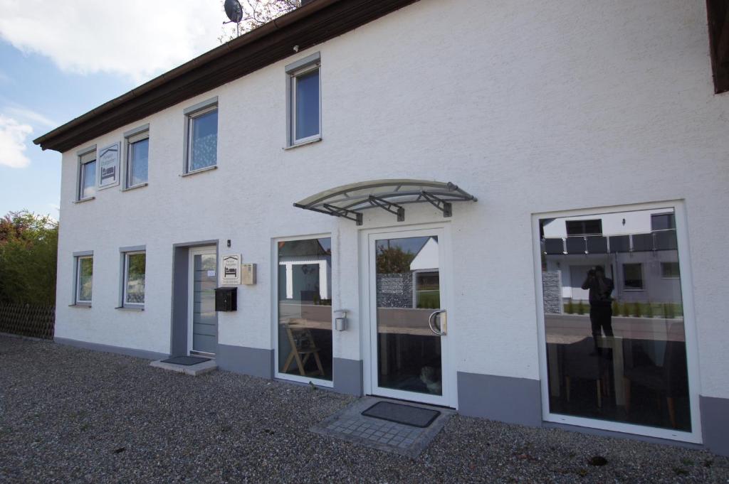 a white building with glass doors and a window at Pension Obstgarten in Laupheim