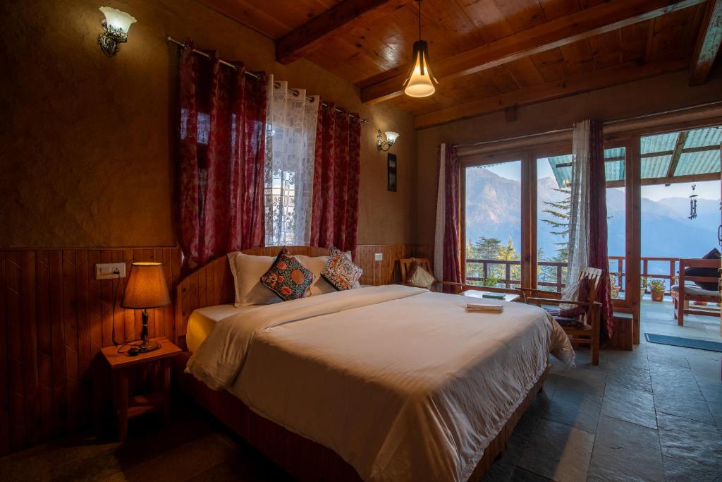 a bedroom with a bed and a large window at Ishan Log Huts-A boutique home stay in Banjār