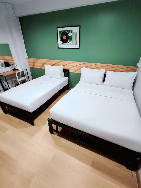 two beds in a room with a green wall at 9TY hotel (ninety hotel) in Bangkok