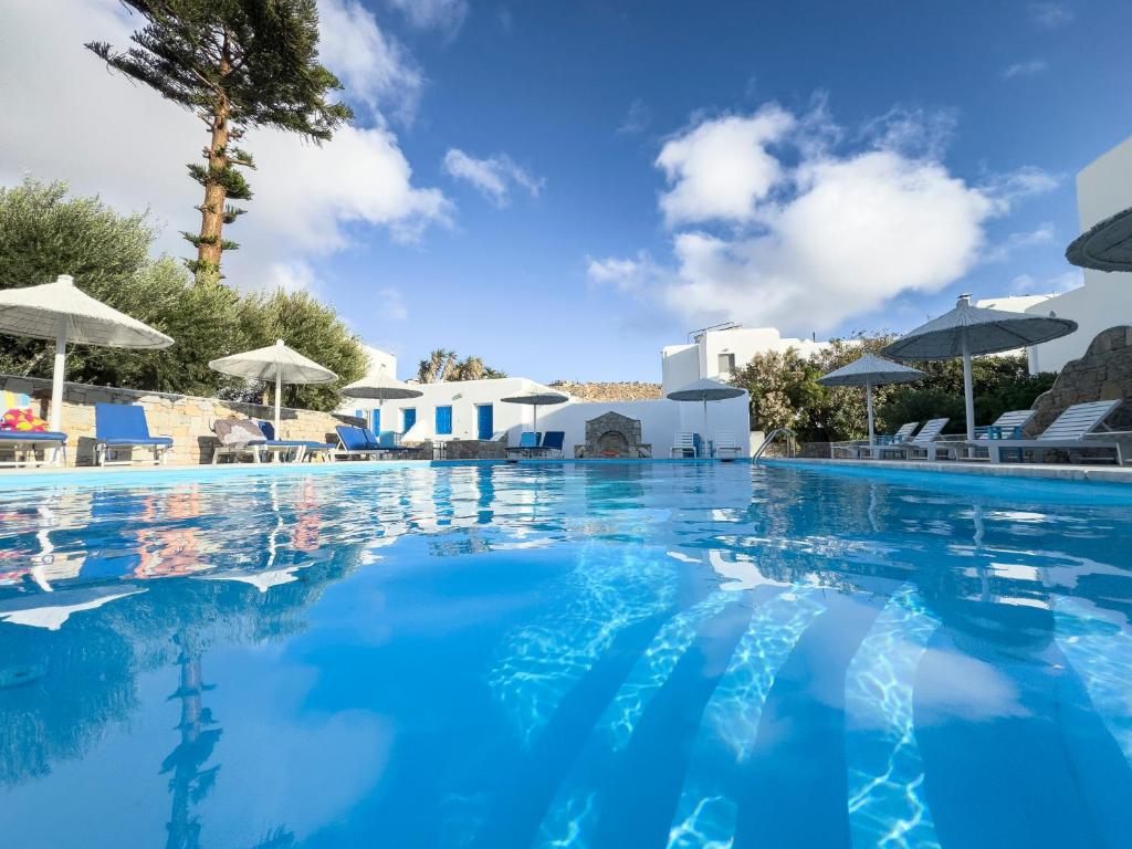a swimming pool with blue water and white buildings at Anemos Hotel & Apartments in Ornos