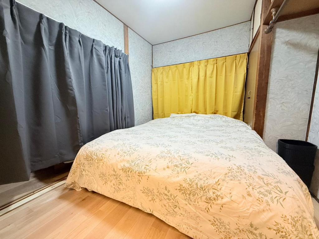 a bedroom with a bed and a yellow curtain at Okayama Urban Peach in Okayama