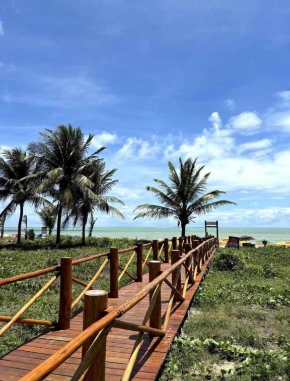 a wooden boardwalk leading to the beach with palm trees at Apartamento Cabedelo João Pessoa in Cabedelo