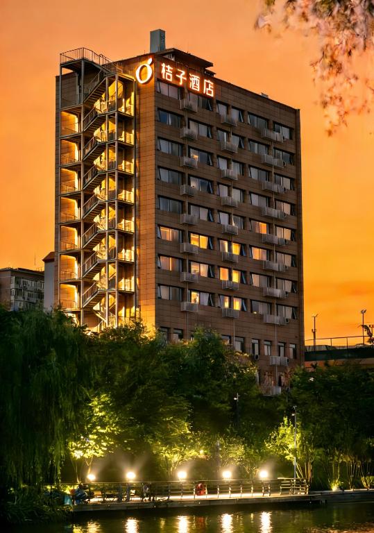 a hotel building with a lit up sign on it at Orange Hotel Beijing Yansha Landmark River in Beijing