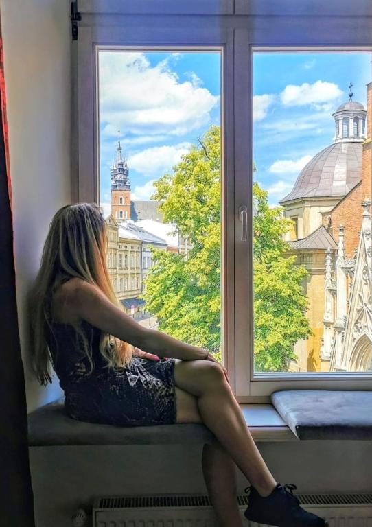 a woman sitting on a window sill looking outside at Otium Old Town Boutique in Krakow
