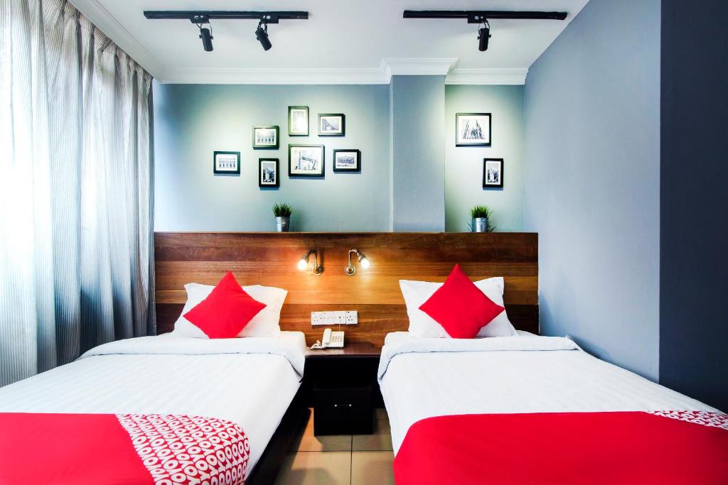 two beds in a room with red and white pillows at OYO 761 City Hotel in Kuala Lumpur