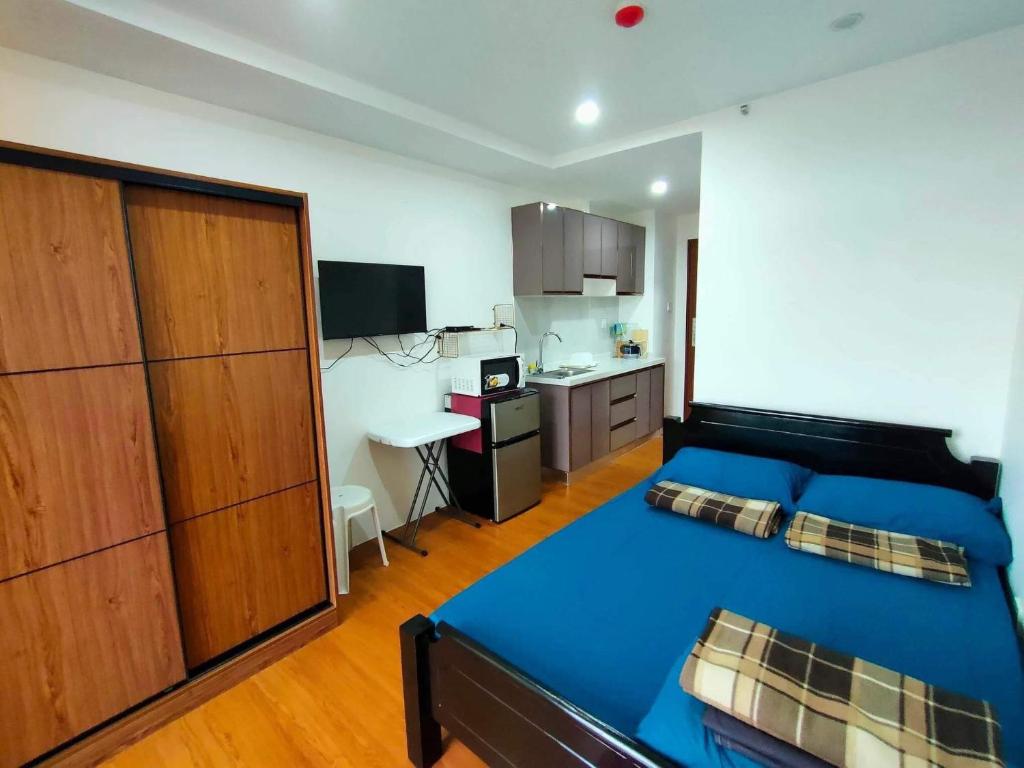 a bedroom with a blue bed and a kitchen at 8F-08 Overlooking Condo at Megatower 3 in Baguio