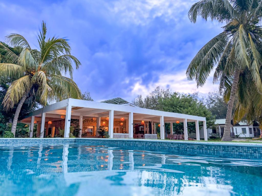 a pool in front of a house with palm trees at Royal Sakalava in Antsiranana