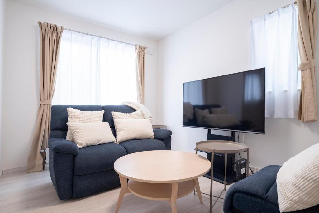 a living room with a blue couch and a tv at 雪舞-YukiMai in Kutchan