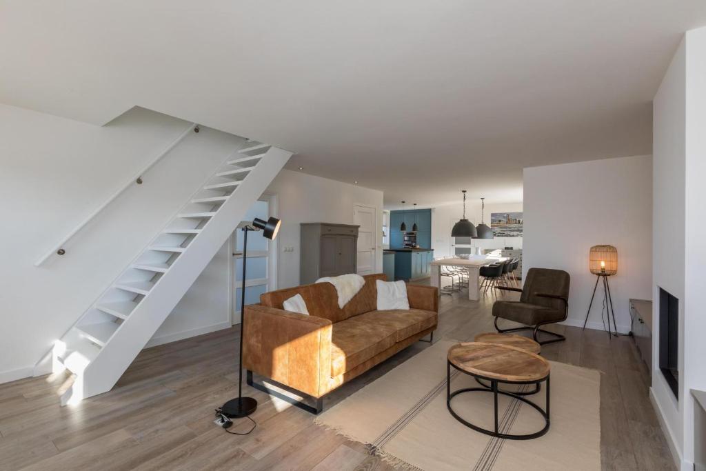 a living room with a couch and a staircase at Welcome in - Familiehuis met ruim terras en speelweide I Oostkapelseweg 32, Serooskerke 'Ooievaar' in Serooskerke