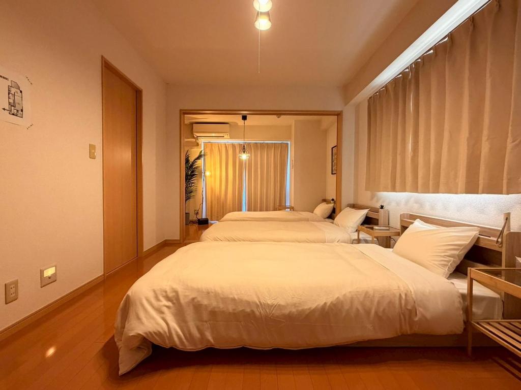 a bedroom with two beds and a window at ura アオトハル2 in Okayama