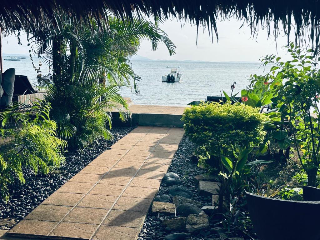 a pathway leading to a beach with a boat in the water at Appartement vue sur mer chez VILLA AMNESYA in Nosy Be