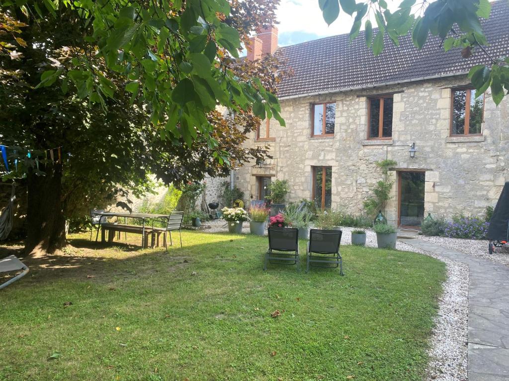 a stone house with two chairs in the yard at Maison de famille du 17ème siècle I Proche Senlis Chantilly Compiègne Astérix Paris in Pontpoint