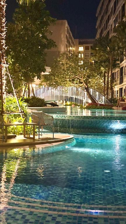 a swimming pool with a bench in a city at night at Dcondo Reef Serenity Condo 2 in Phuket