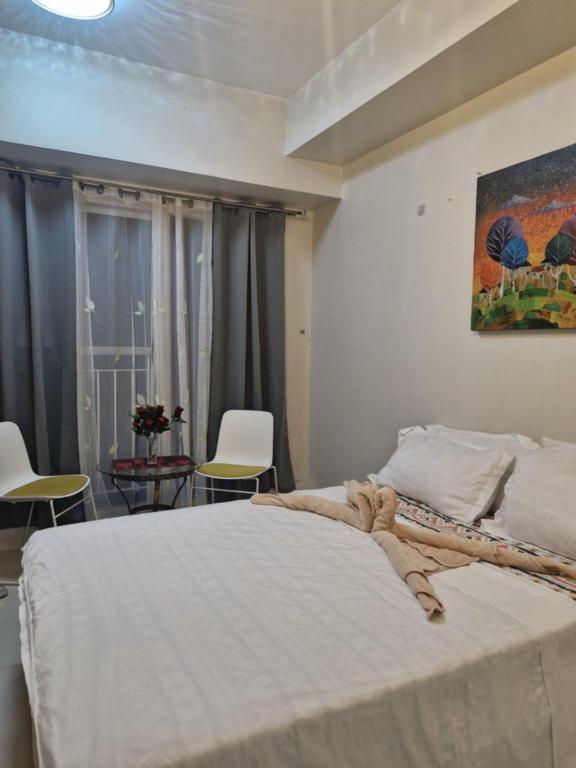 a bedroom with a bed with chairs and a painting on the wall at Crystal Suites I Partial Taal View in Sampong