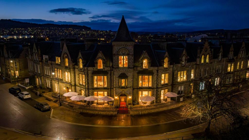an old building with lights on in a city at night at The Ambassador Hotel in Inverness