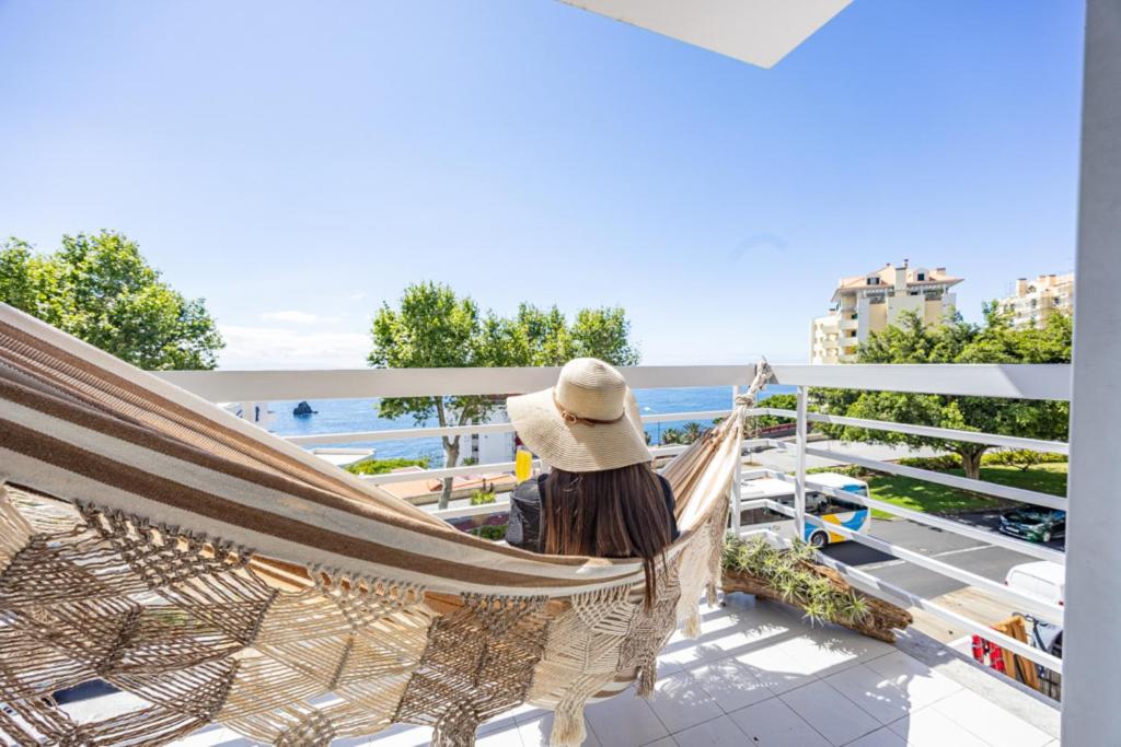 a woman sitting in a hammock on a balcony overlooking the ocean at Ocean Lido in Funchal