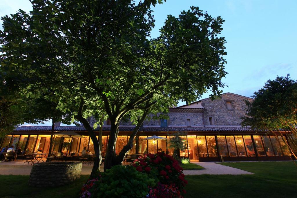 un edificio con un árbol y flores delante de él en Michel Chabran - Teritoria, en Pont-de-lʼIsère