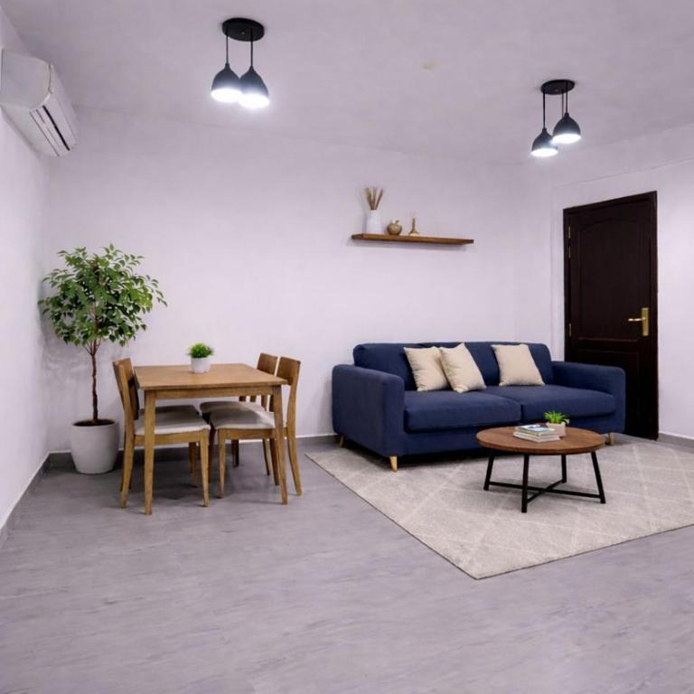a living room with a blue couch and a table at Majd Lux Stay in Ma‘ābīlah