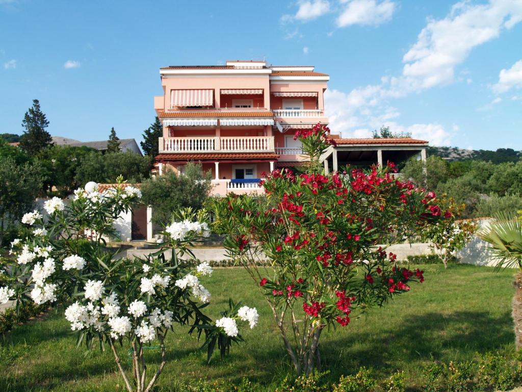 a house in the middle of a field with flowers at Apartments Banic in Rab