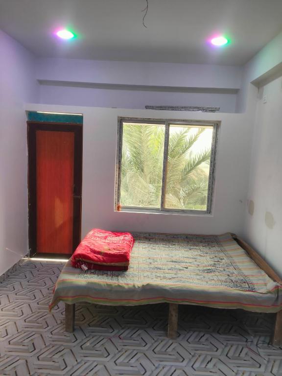 a bed in a room with a window at Laxmi Narasimha Hotel in mayapur