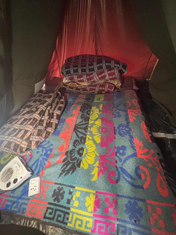 a bed in a tent with a comforter on it at Kedar cloud camp in Kedārnāth