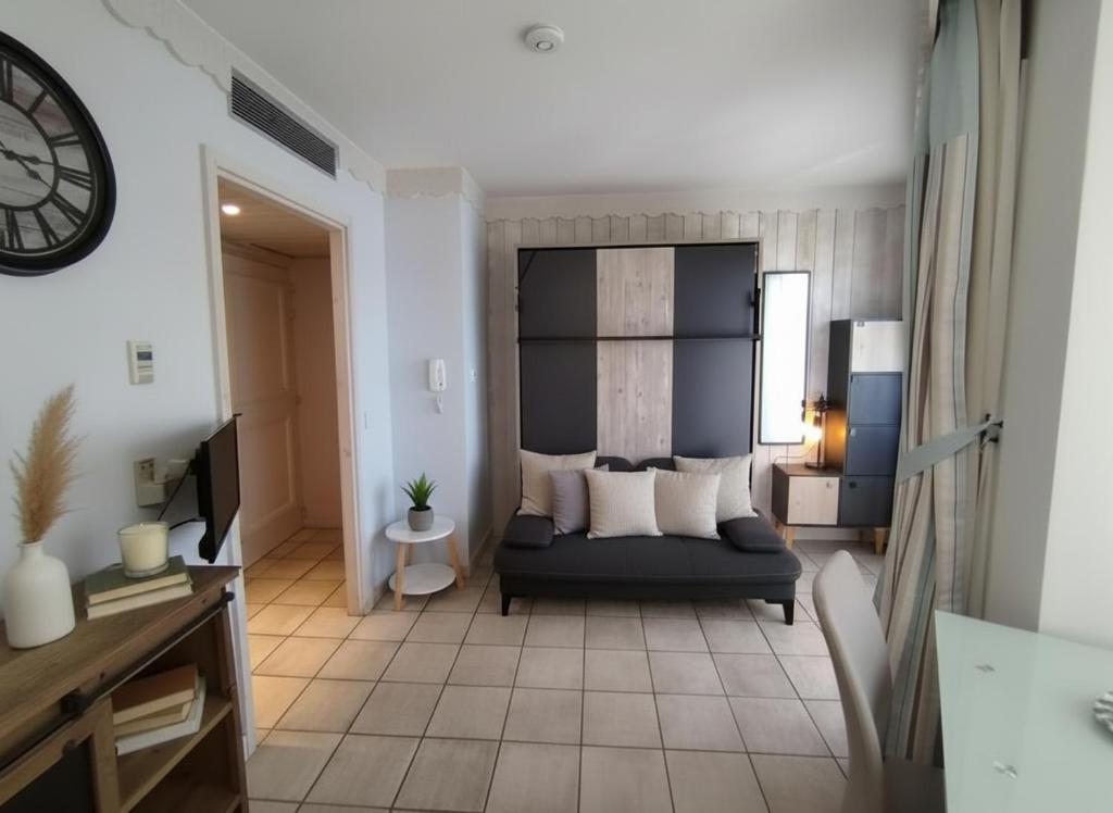 a living room with a couch and a clock at Reflets du Lac Annecy, Baie des Voiles - Vue Lac - Terrasse - Plage & Parking Privés in Duingt