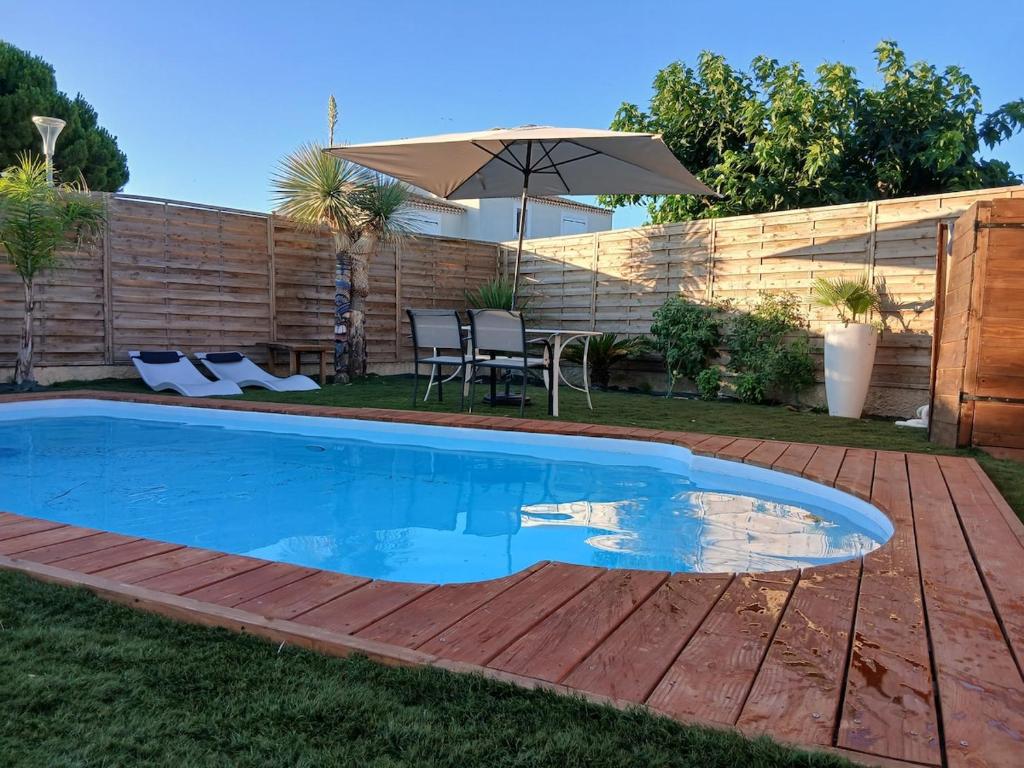 a swimming pool in a yard with an umbrella at Air-conditioned villa with pool in Mèze