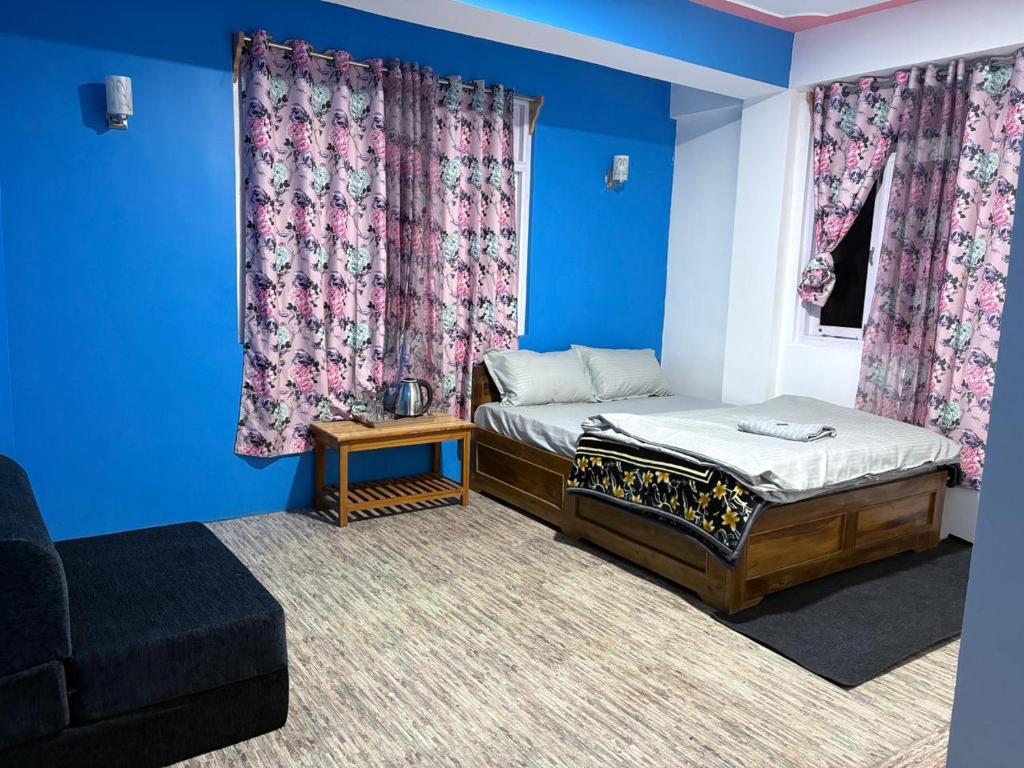 a room with two beds and a couch and blue walls at Mayal Lyang Lachung in Mangan