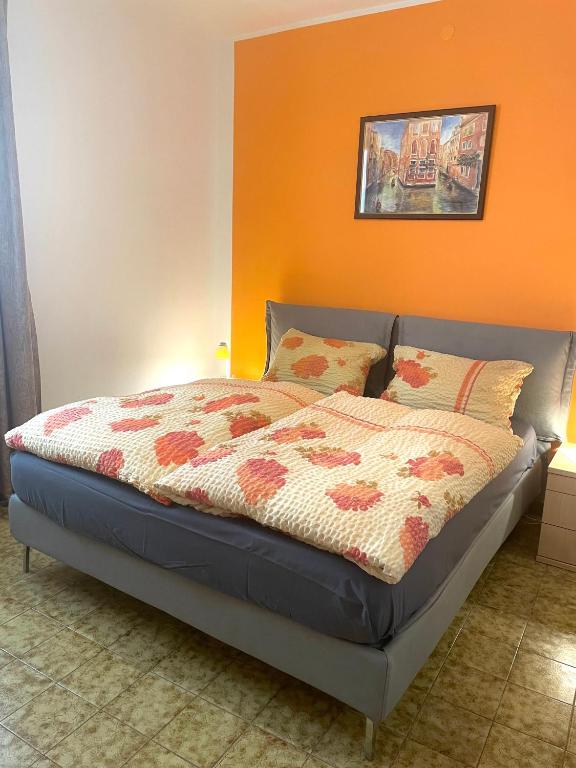 a bed in a bedroom with an orange wall at Casa Sponchie in Lazise