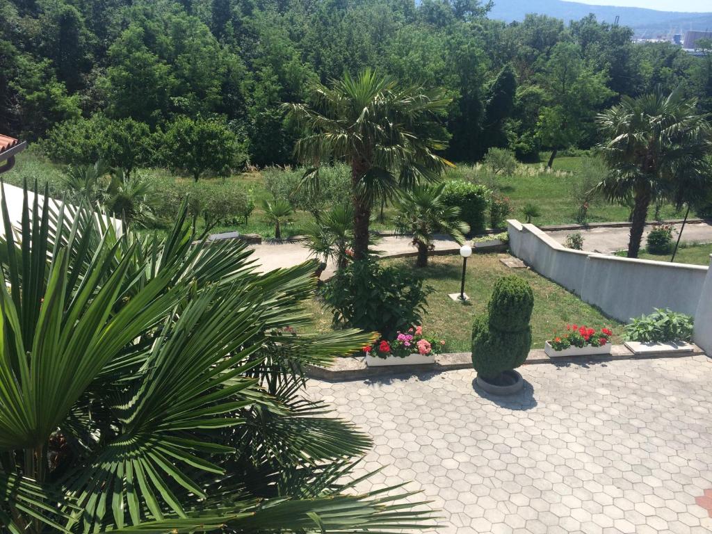 un jardín con palmeras y flores y una valla en Apartments Lili, en Ankaran