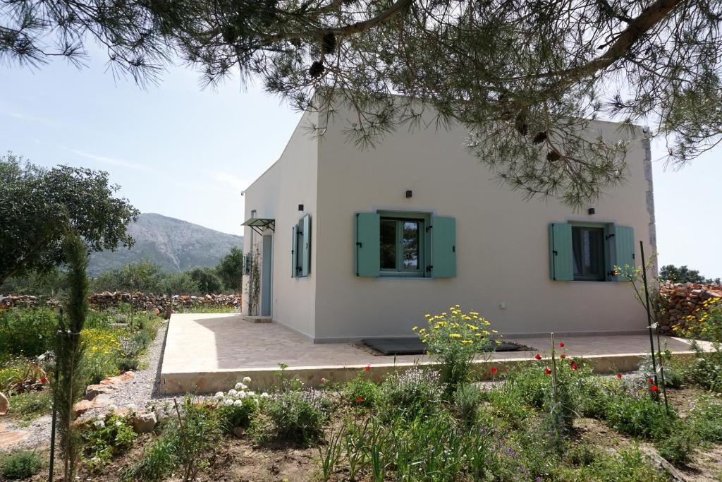 a small white building with green shuttered windows at Villa Tsakalaki in Stavríon