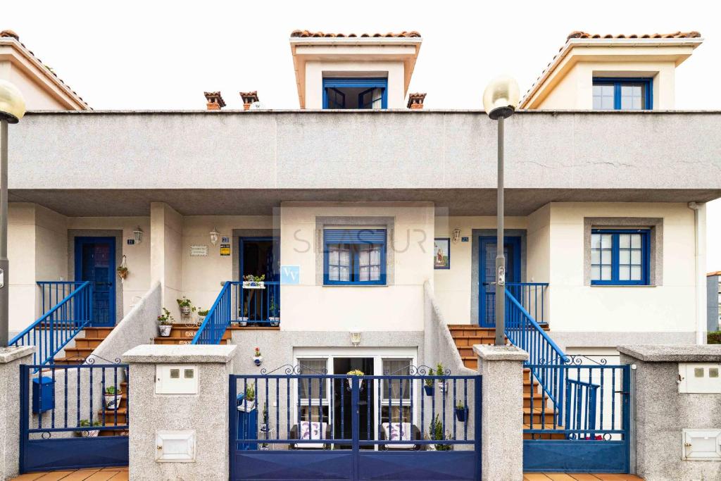 a large white house with blue gates at La Casina Azul de May By Silastur in San Juan de la Arena