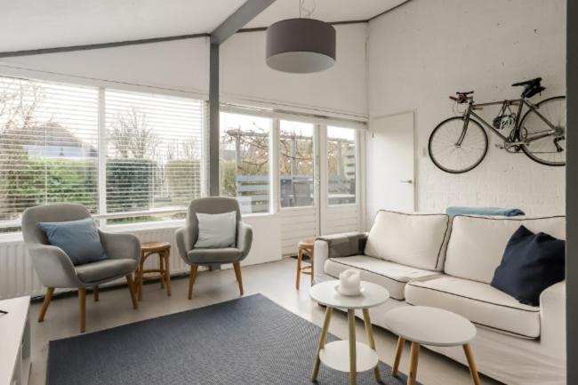 a living room with a couch and chairs and a bike on the wall at Rekerlanden 90 in Schoorldam