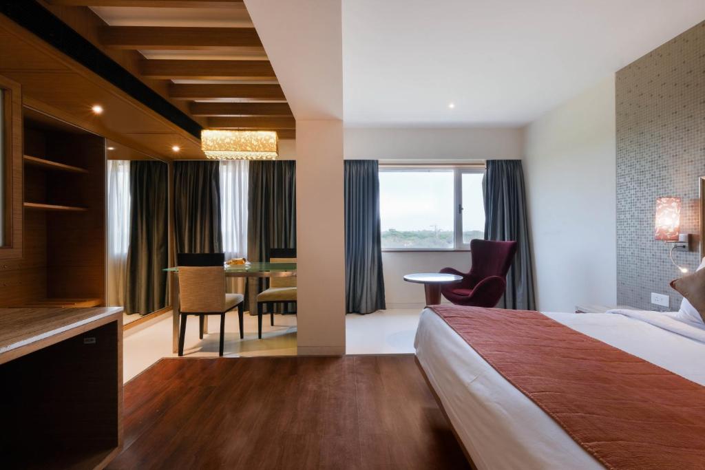 a hotel room with a bed and a table and chairs at 7 Apple Hotel - Viman Nagar Pune in Pune