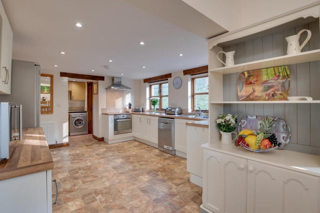 a large kitchen with white cabinets and tile floors at 3 Bed in South Molton oc-millba in Bishops Nympton