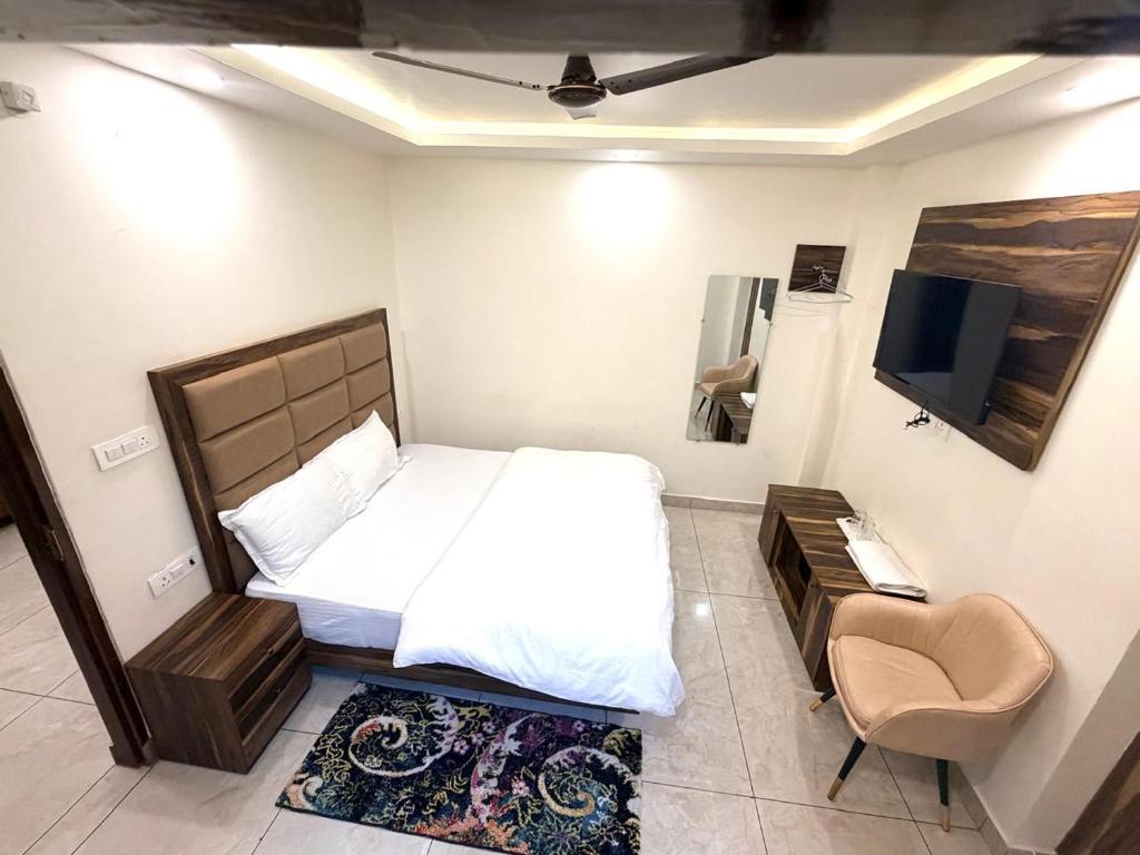 a bedroom with a bed and a tv and a chair at GRACE Inn in Dehradun