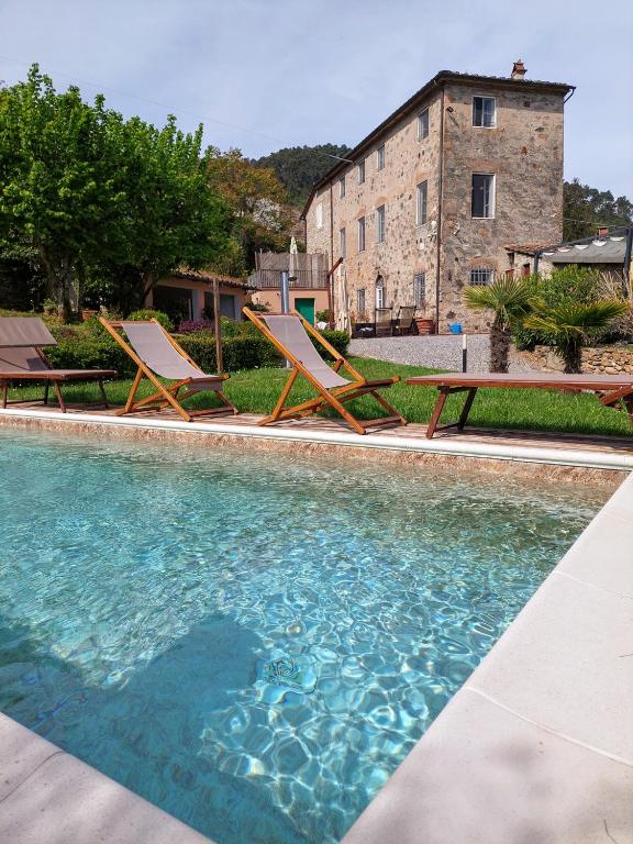 two lounge chairs and a pool in front of a building at Casa Locci in Capannori