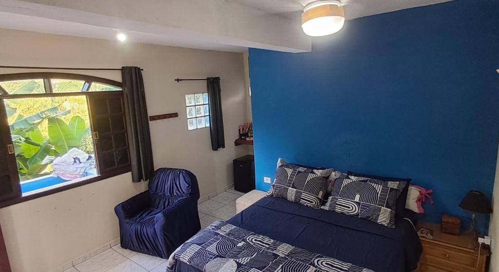 a bedroom with a bed and a blue wall at Rancho e Pesqueiro do Cowboy in Piedade