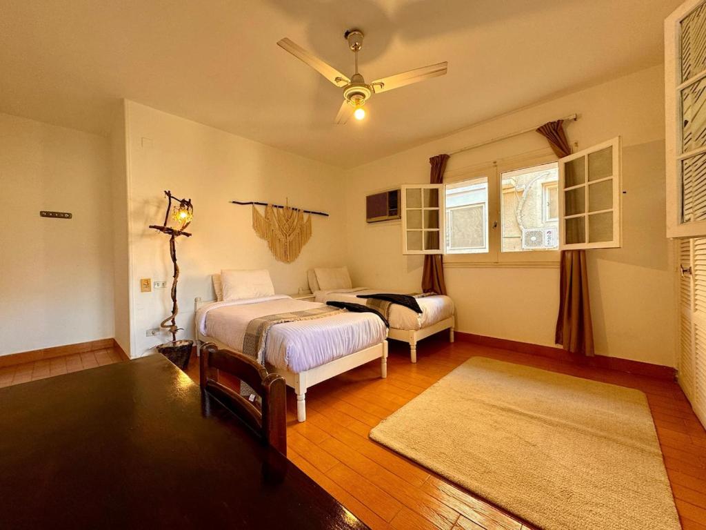 a bedroom with two beds and a ceiling fan at Villa Maadi 35 - R 205- Pool View Room in Cairo