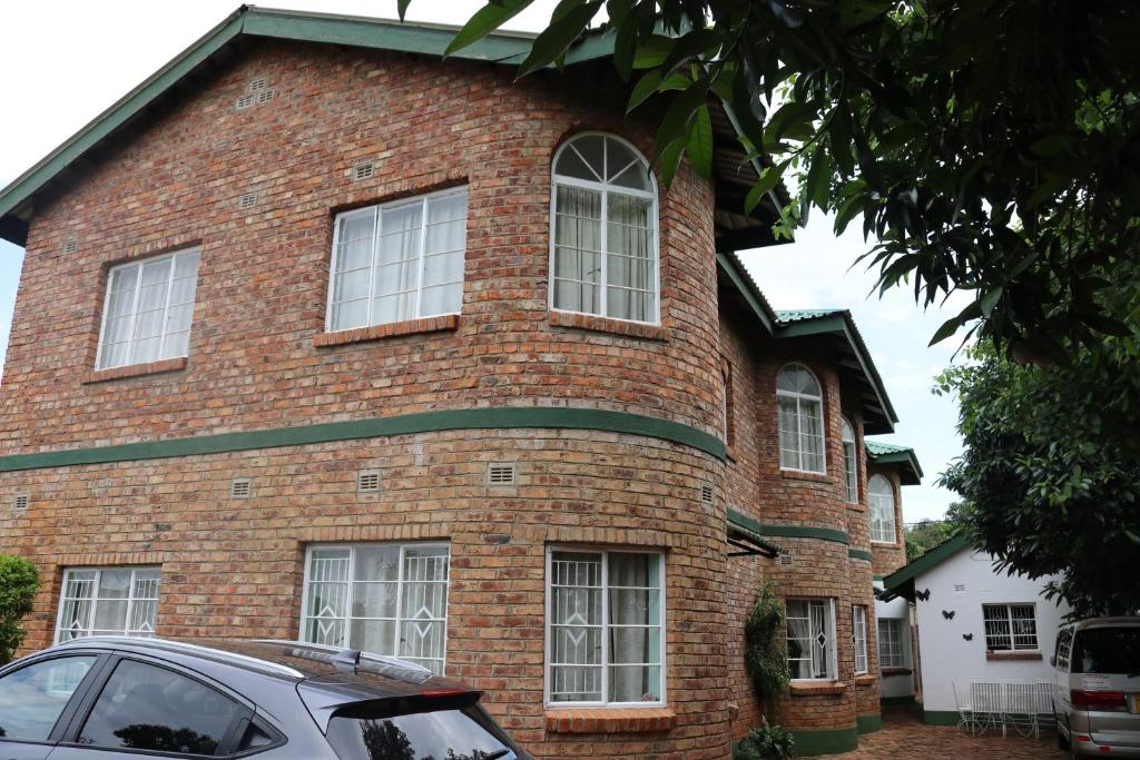 a brick house with white windows and a car parked in front at Joyful Vista Guest Lodge in Victoria Falls