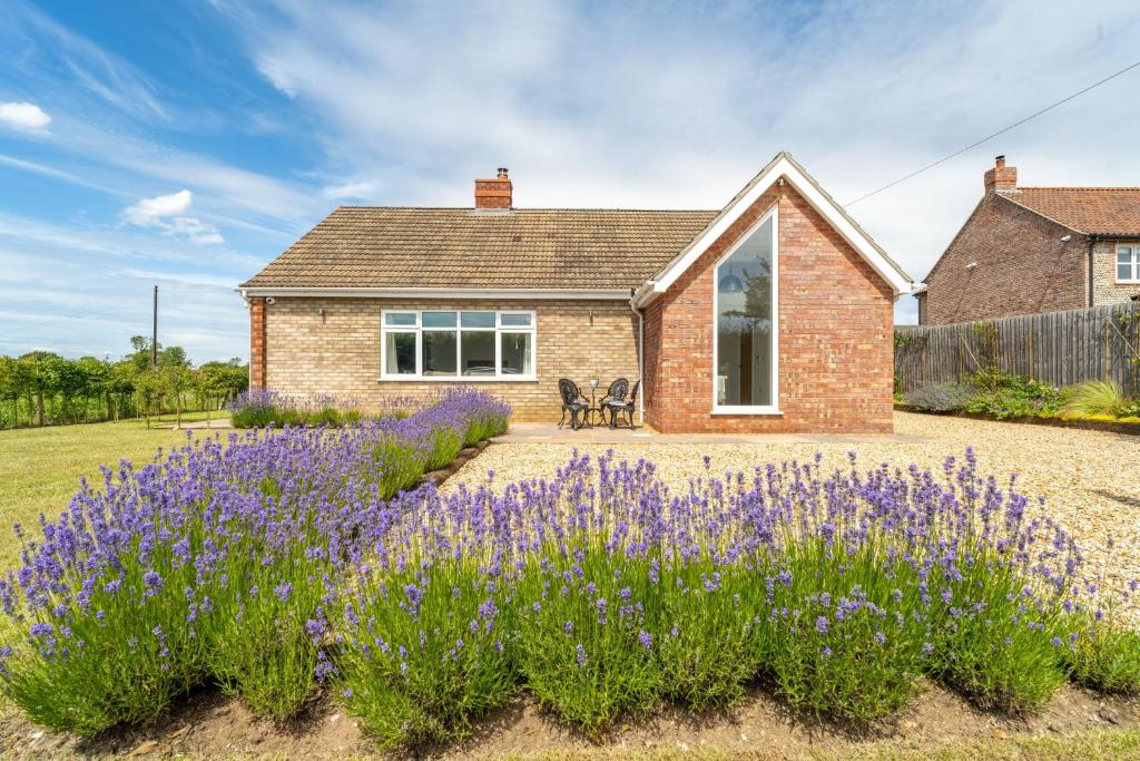 a house with purple flowers in front of it at Deerwood in Grimston