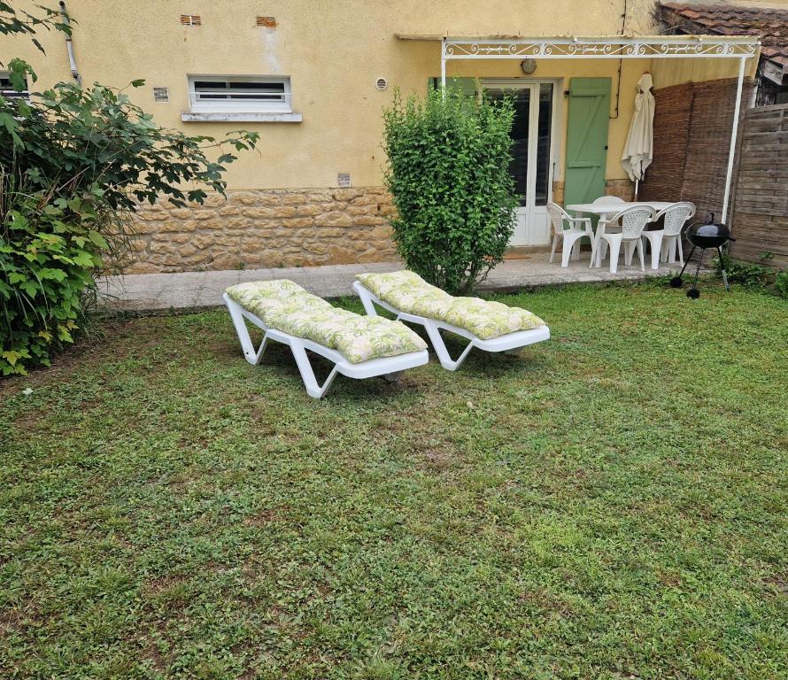 two white benches sitting on the grass in a yard at Montignac, t2 proche Lascaux in Montignac