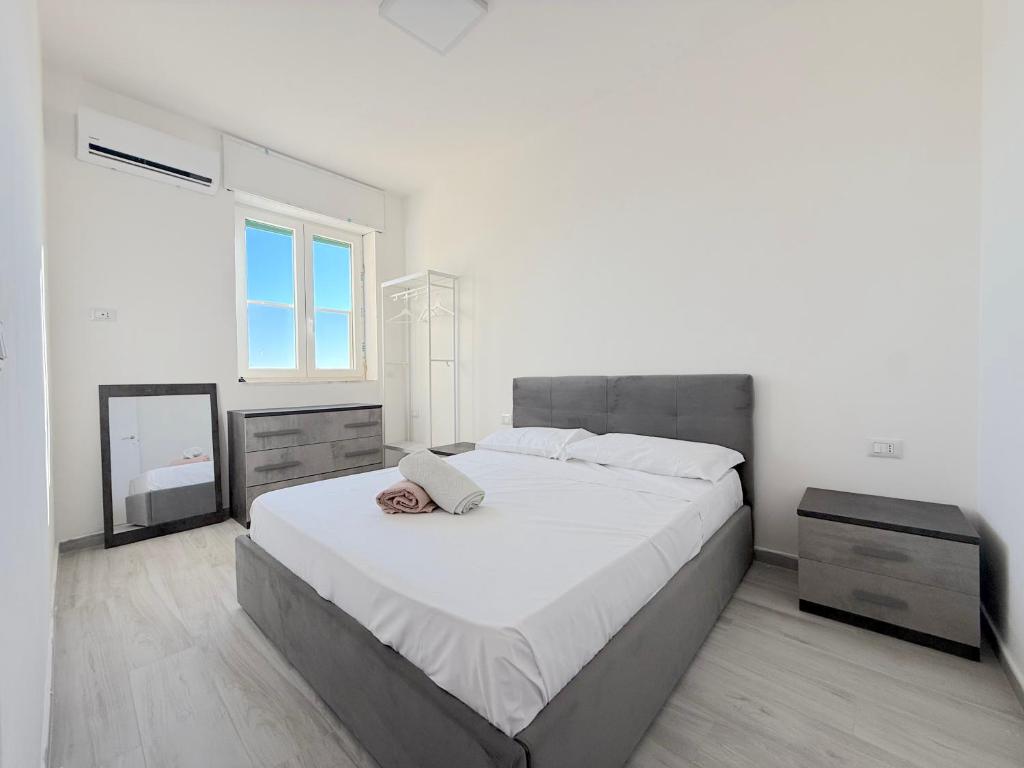 a white bedroom with a large bed and a mirror at Casa Tonia - Baia Verde in Baia Verde