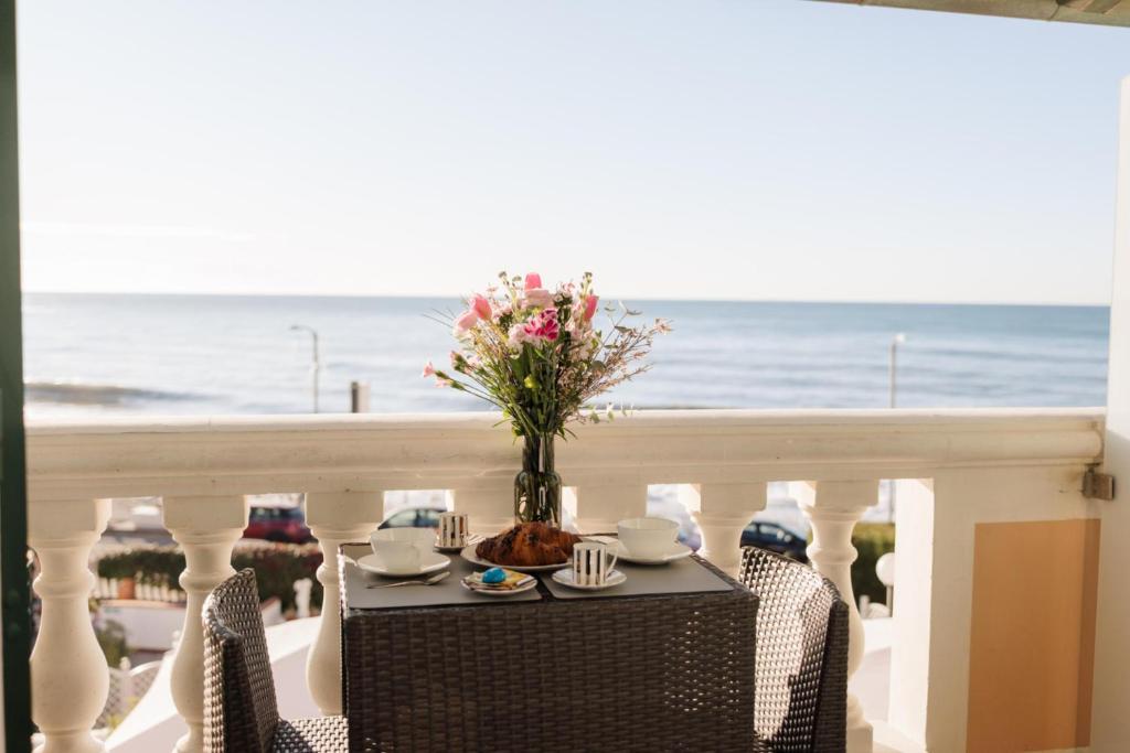 a table with a vase of flowers on a balcony with the ocean at Del Prado in Riva Ligure