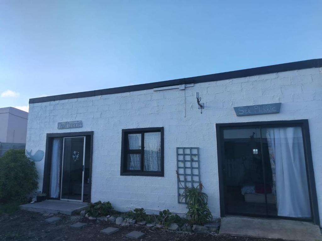 a white brick building with two windows and a door at Cocos Island in Bettyʼs Bay