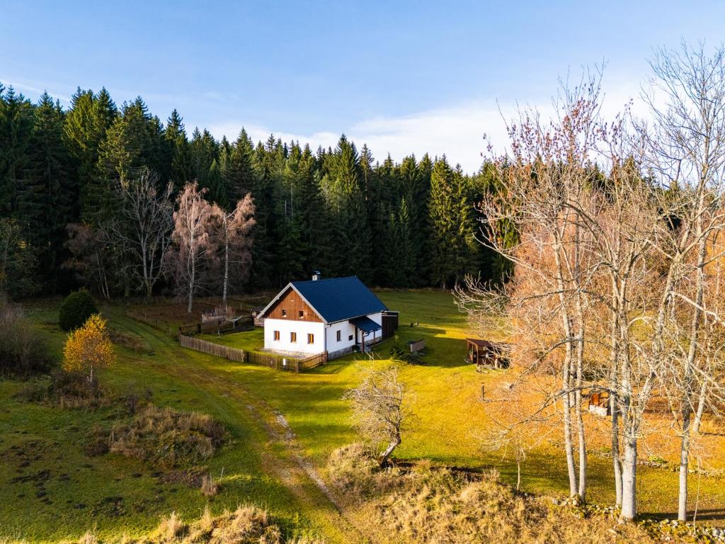 a small white house on a green field with trees at Chalupa Sibřinka in Korkusova Huť