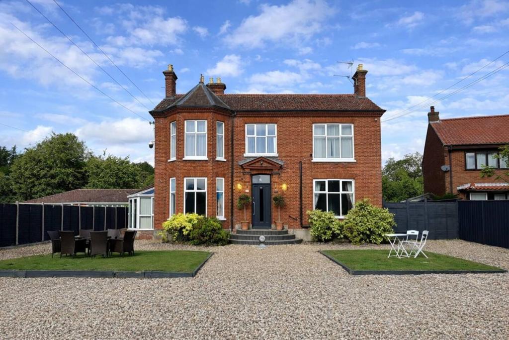 a red brick house with a fence in front of it at Spacious Buxton house with hot tub and pool table in Norwich
