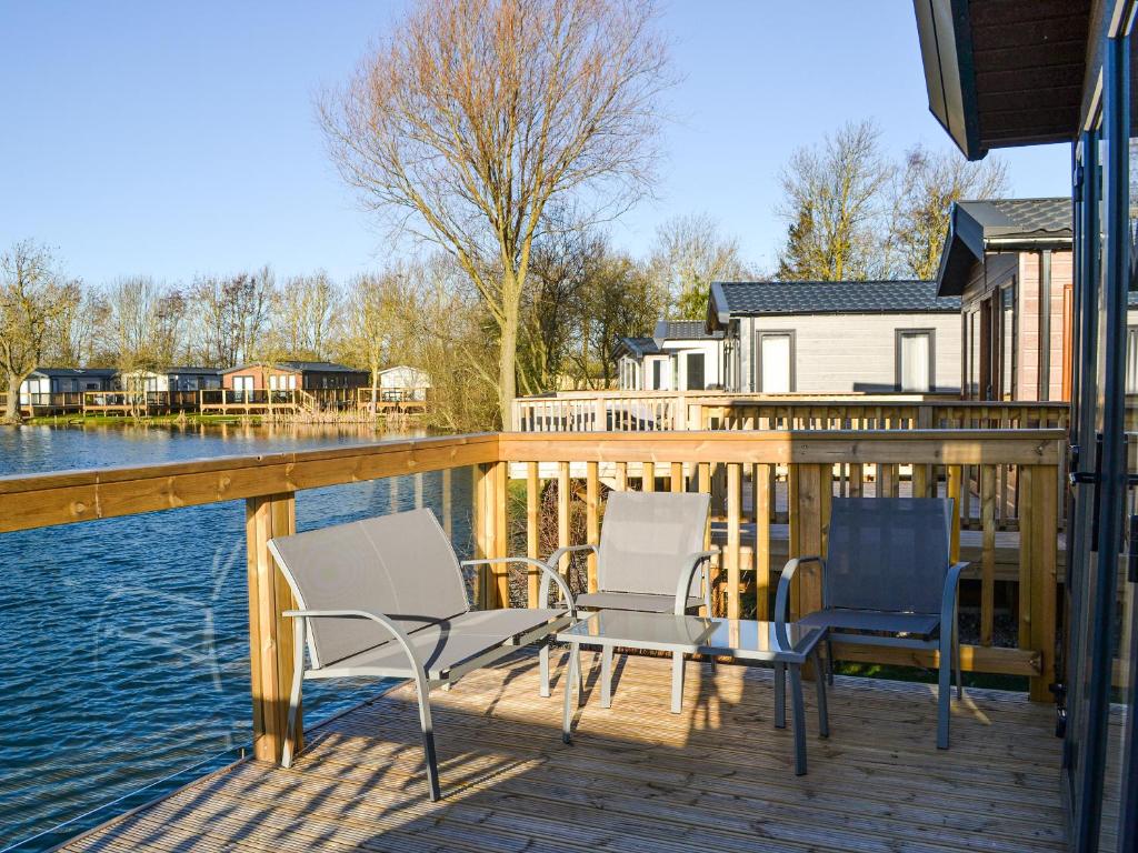 two chairs and a table on a deck next to the water at Waterfoot Lodge W09 in Amotherby