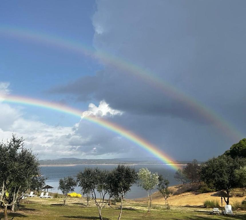 a rainbow in the sky over a body of water at Markádia in Alvito