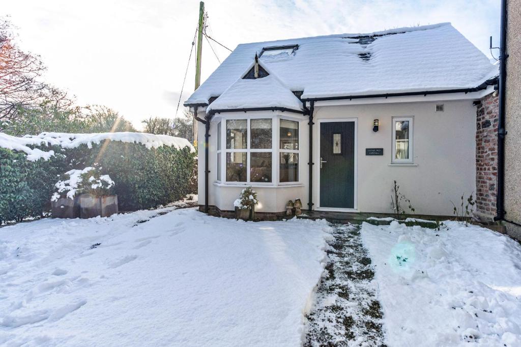 a small white house with snow on the ground at Finest Retreats - Cedar Tree Cottage in Clocaenog